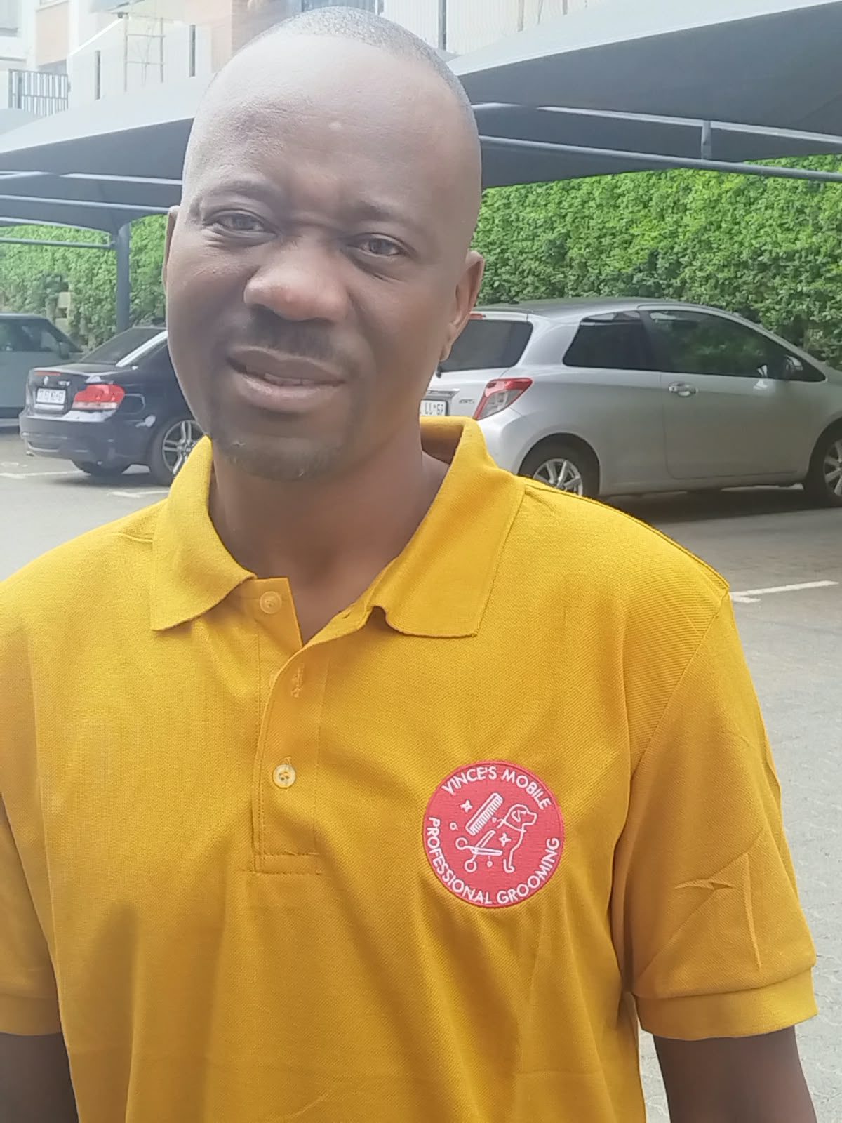 A Vince Mobile Dog Grooming groomer in a branded shirt outside a client’s home